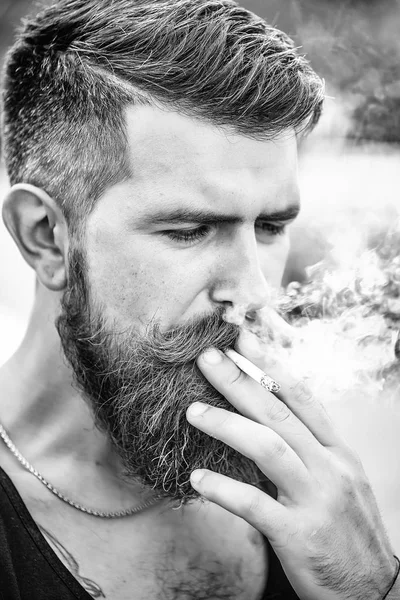 眉をひそめているひげを生やした男はタバコを吸って — ストック写真