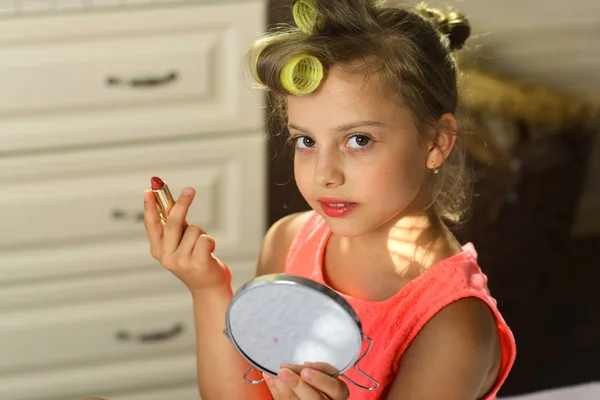 Kind met roze lippenstift en spiegel draagt trendy jurk — Stockfoto