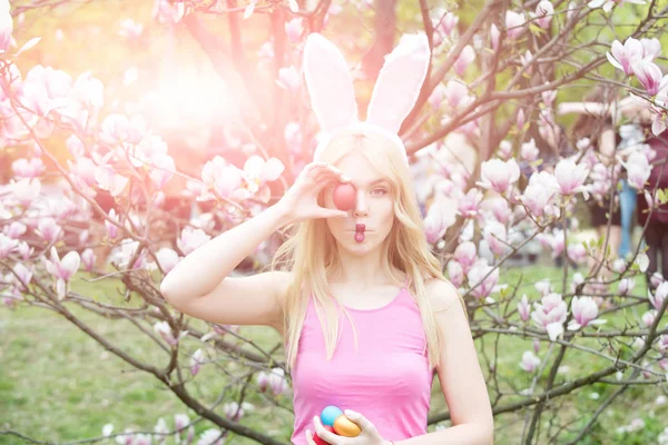 Sensuele vrouw in magnolia met kleurrijke eieren. — Stockfoto