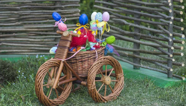 Wicker tricycle with easter basket on grass