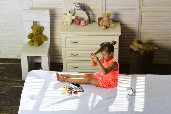 Kind zit op bed met felle lippenstift en schoonheidsmiddelen in childroom — Stockfoto