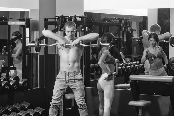 Muskulös man och flicka på gym med hantlar och skivstång — Stockfoto