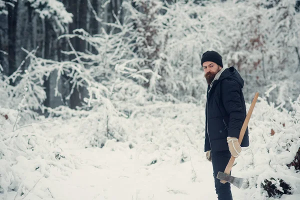 Homem barbudo com machado na floresta nevada . — Fotografia de Stock