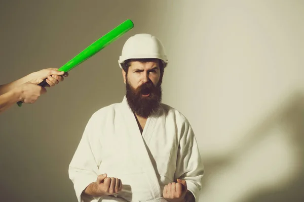 bearded shouting karate man in kimono, helmet with baseball bat