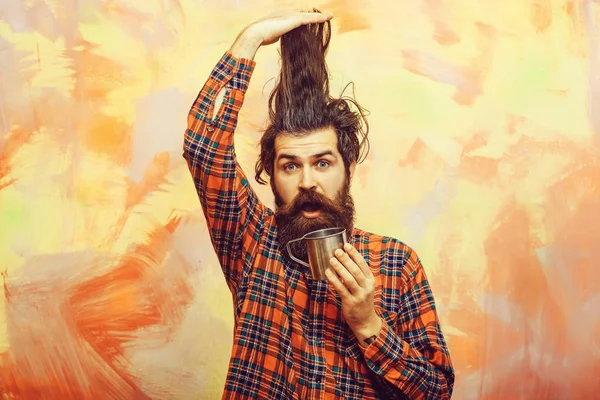 Γενειοφόρος άνδρας κρατώντας τα μαλλιά κομψά κρόσσια και μεταλλικές κούπα — Φωτογραφία Αρχείου