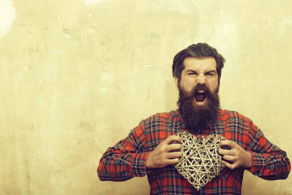 Angry bearded man with long beard holds wicker heart