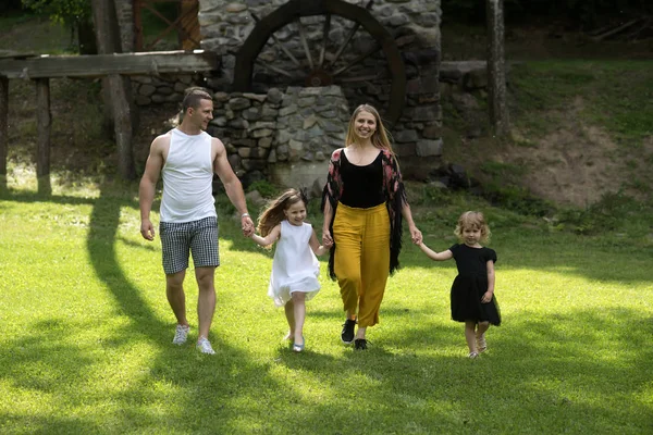 Çocuklar ve ebeveynler yeşil çimenlerin üzerinde yürüyelim. Özgürlük, etkinlik, yaşam tarzı, enerji kavramı. Kızlar, kadın ve erkek yaz peyzaj gülümse. Mutlu çocukluk, Aile, aşk. Anneler ve babalar günü.