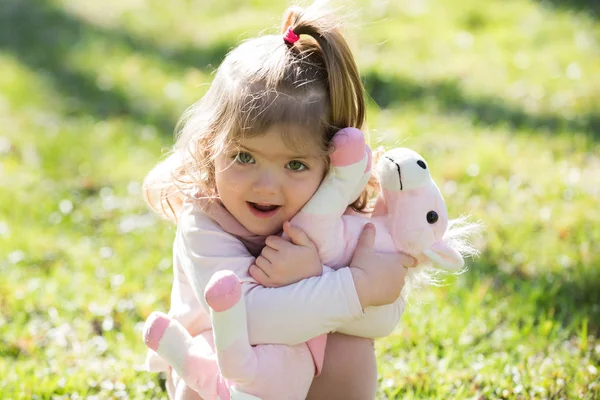 Bebê menina abraço brinquedo cavalo macio no dia ensolarado — Fotografia de Stock