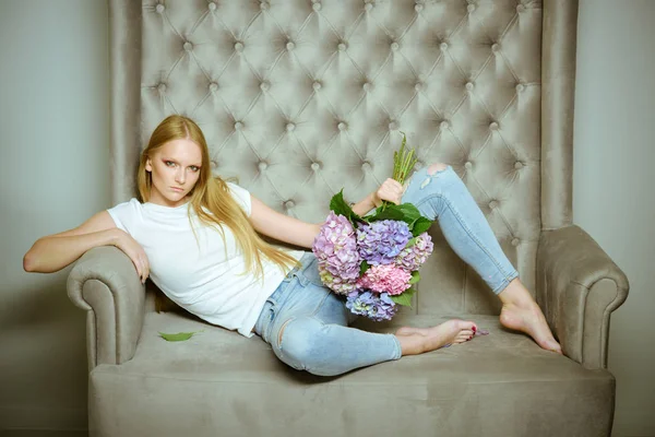 Жінка з квітами гортензії розслабляється на дивані — стокове фото