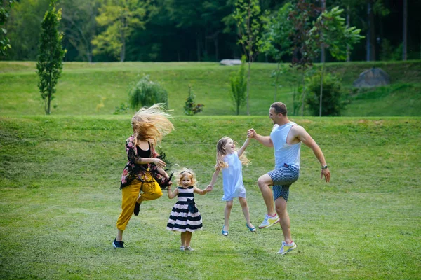 女の子 女と男は 夏の風景に笑顔します 子供と親は 緑の芝生にジャンプします 幸せな子供時代 母親と父親の日 自由活動 ライフ スタイル — ストック写真