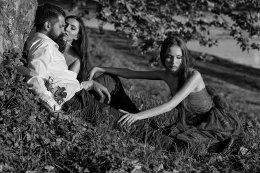 Sakallı adam ve iki kadınla çimenlerin üzerinde