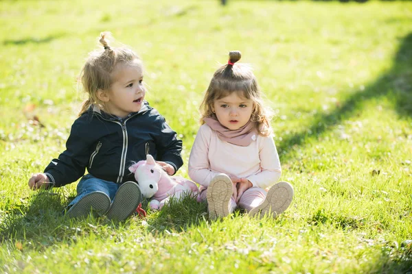 Mädchen und Junge sitzen im grünen Gras — Stockfoto