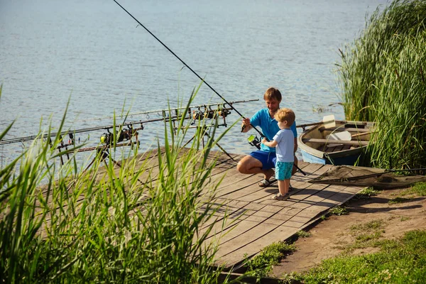 Отец учит маленького сына ловить рыбу в пресной воде — стоковое фото