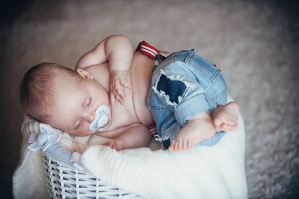 Nyfött barn i jeans sova i korgen på golvet — Stockfoto