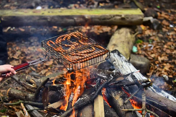 Autumn barbecue in nature - sausages fried on fire. — Stock Photo, Image