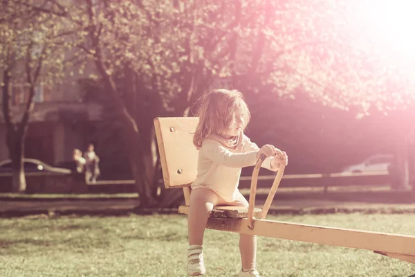 Flickan sitter på gungbräda på solig dag — Stockfoto