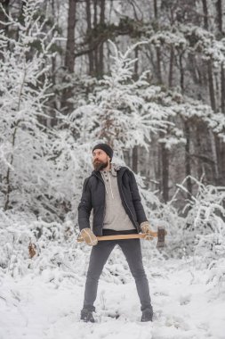 Sakallı adam karlı ormanda balta ile.