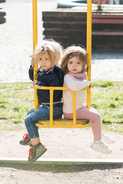 Jongen en meisje op schommel op zonnige dag — Stockfoto