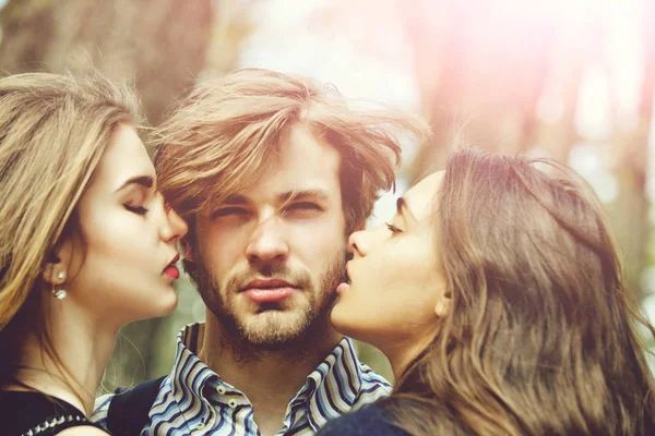 两个漂亮的女孩吻留着胡子的英俊男人 — 图库照片
