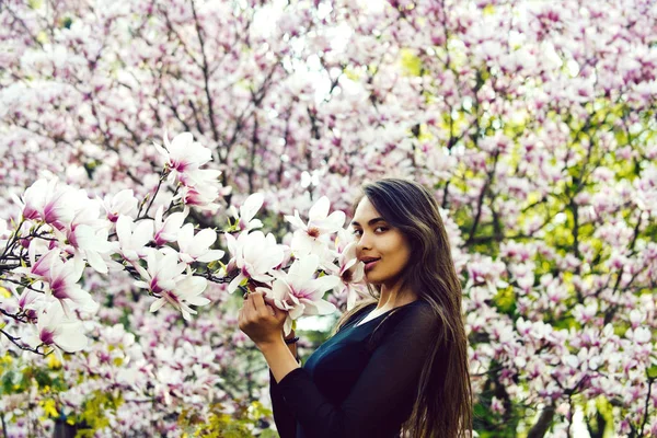 Mulher com cabelo longo e morena posando na árvore de magnólia — Fotografia de Stock