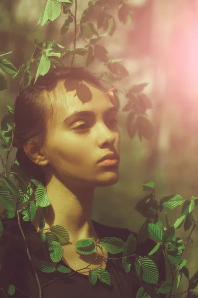 girl with adorable face posing in green leaves