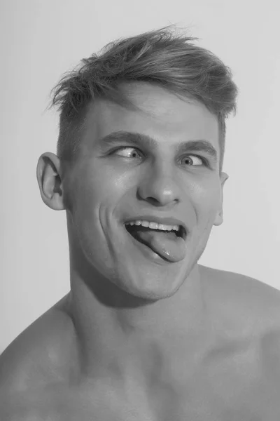 Hombre entrecerrando los ojos y mostrando la lengua en la cara divertida — Foto de Stock