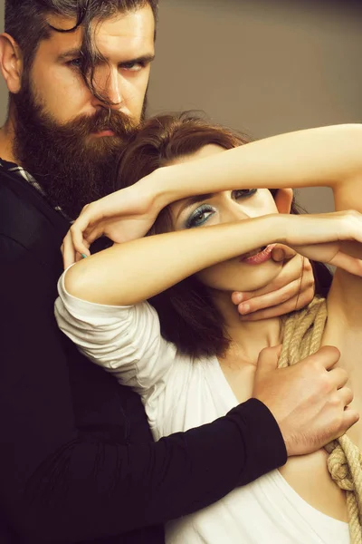 裸の胸でかなり裸の女性の若いカップルは 灰色の背景に女性の胸に触れる長いひげのハンサムな髭の男の手とロープ — ストック写真