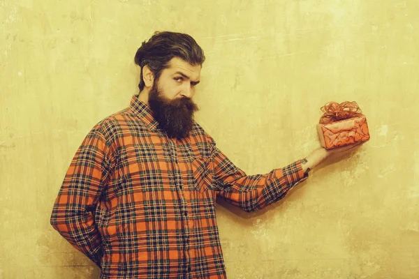 Нахмуренный бородатый мужчина с длинной бородой держит красную коробку подарков — стоковое фото