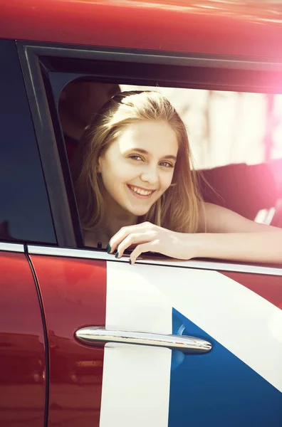 Glückliches hübsches Mädchen mit nachdenklichem Gesicht, das durch das Autofenster blickt — Stockfoto