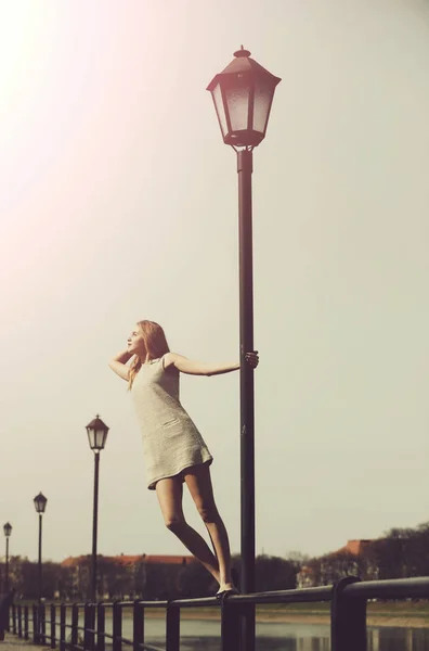 Mooi meisje staan hoog op straat lantaarnpaal — Stockfoto