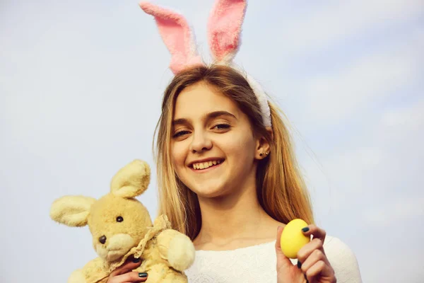 Счастливая пасхальная девушка с кроличьими ушами, яйцо на голубом небе — стоковое фото