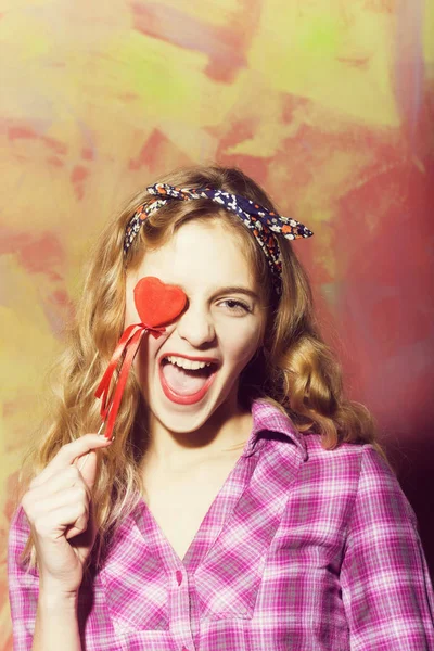 Excited pretty girl laughs with red heart on stick — Stock Photo, Image