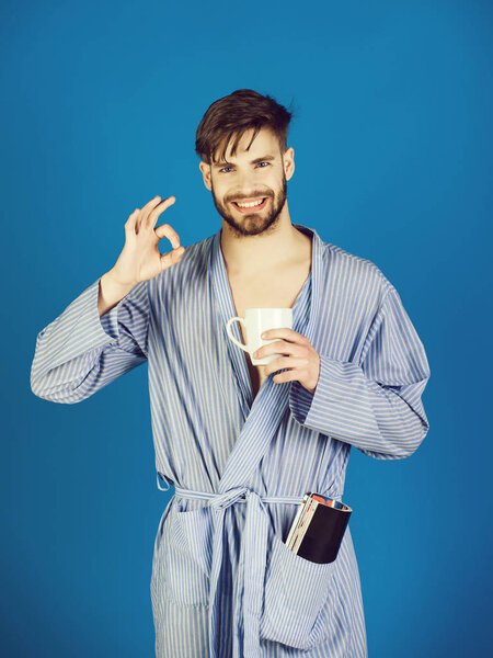 relax of smiling man in bathrobe holding cup of coffee