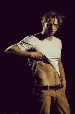 Beyaz tişörtlü yakışıklı adam seksi, kaslı gövdesini gösteriyor.