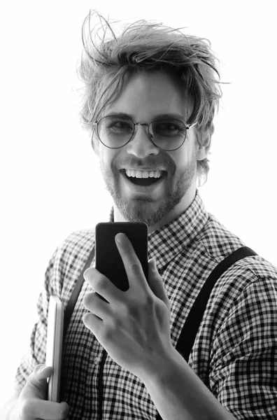 Komea mies silmälasit älypuhelimella ja kannettavalla tietokoneella — kuvapankkivalokuva