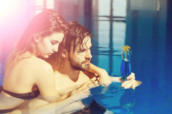 肌肉男和带有鸡尾酒的蓝色水池中的性感女人 — 图库照片