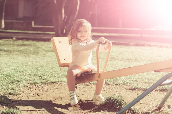 Girl smile on seesaw on sunny day — Stock Photo, Image