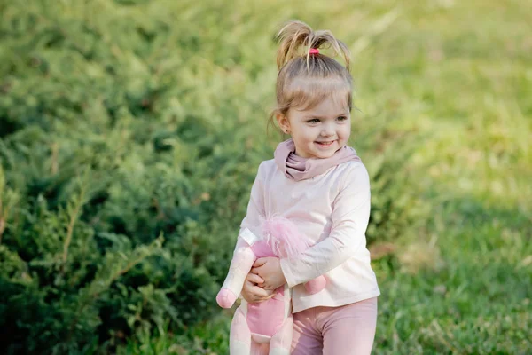 Menina feliz com sorriso de brinquedo macio no fundo natural — Fotografia de Stock