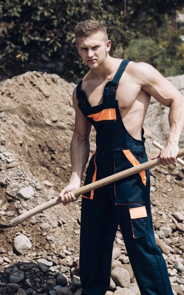 Muscular builder on sunny day works at construction site. — Stock Photo, Image