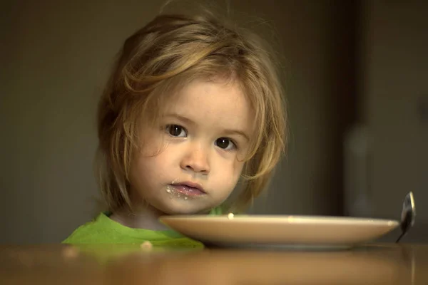 Child with empty plate, spoon after eating — Stock Photo, Image