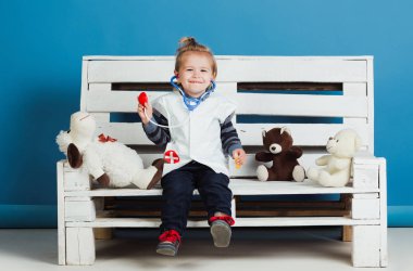 Evcil hayvan tahta bankta oturmak oyuncak ile mutlu çocuk