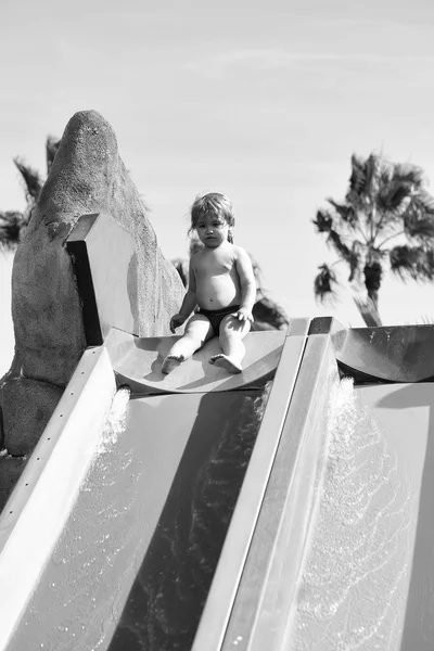 Lindo bebé niño se sienta en la parte superior del tobogán de agua —  Fotos de Stock