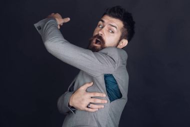 Sakallı adam koyu arka plan üzerinde delik ile ceket giyer.