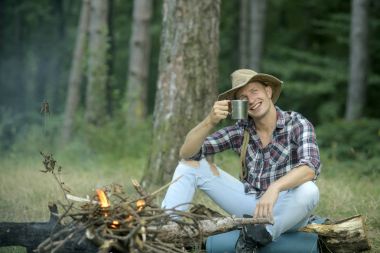 Şapkalı adam şenlik defocused arka plan, ağaçta oturuyor..