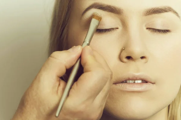 Chica consiguiendo sombra de ojos en polvo en los párpados con cepillo —  Fotos de Stock