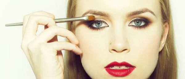 Chica con labios rojos aplicando sombras de ojos con cepillo de maquillaje — Foto de Stock