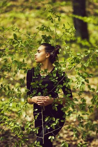 girl hiding in fresh, young, green tree leaves