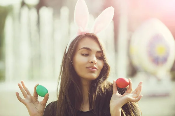 Chica alegre con orejas de conejo rosado posando con huevos de colores , —  Fotos de Stock