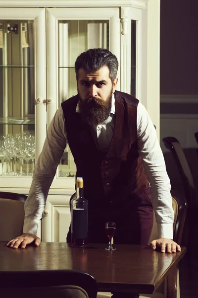 Man standing at table served with glass and bottle