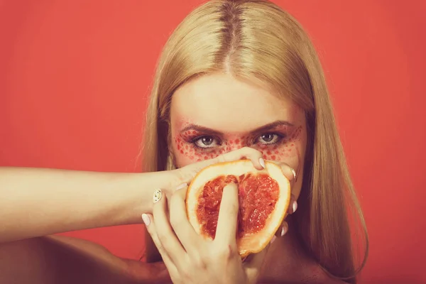 Grapefruit in den Händen einer Frau mit kreativem modischen Make-up, v — Stockfoto